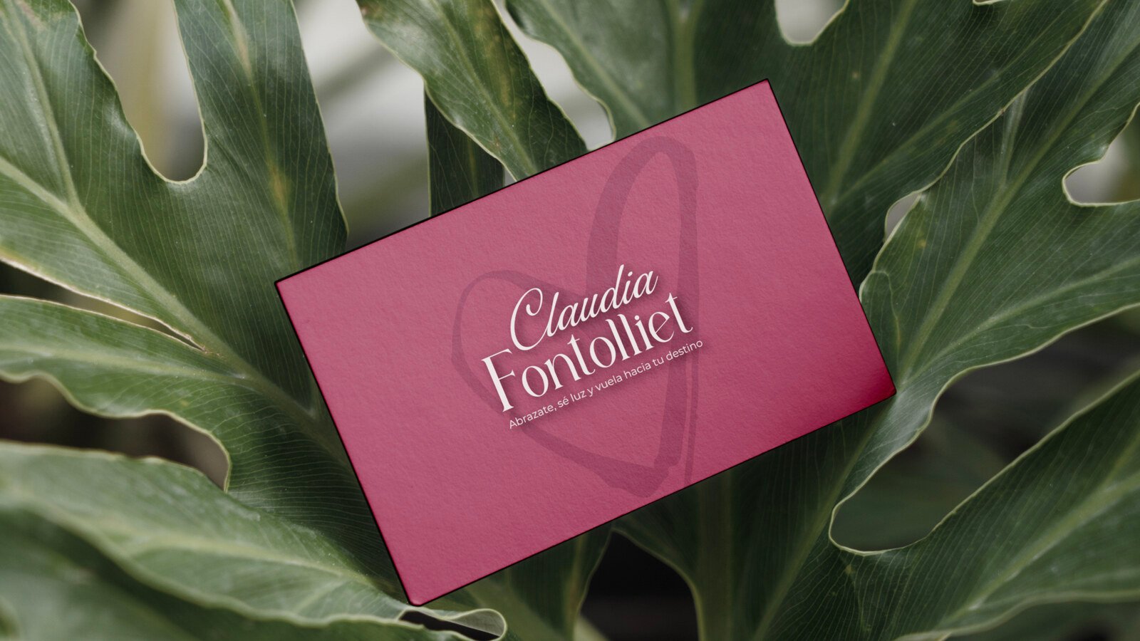 Tarjeta burdeos sobre una hoja de monstera