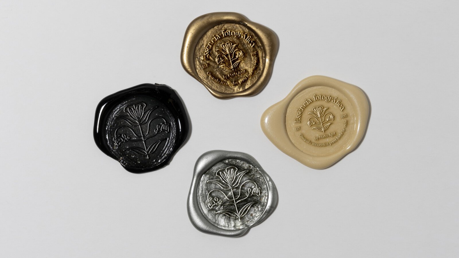 Cuatro sellos de lacre con el emblema en negro, oro, arena y plata